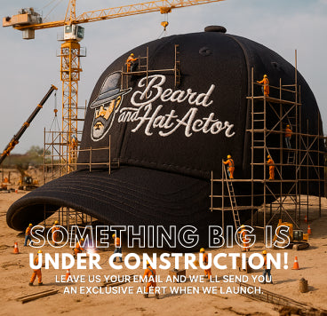 Creative image of a construction site with tiny workers building around a giant black baseball cap embroidered with the Beard and Hat Actor logo. A crane operates in the background. Overlay text reads: “Something Big is Under Construction.”