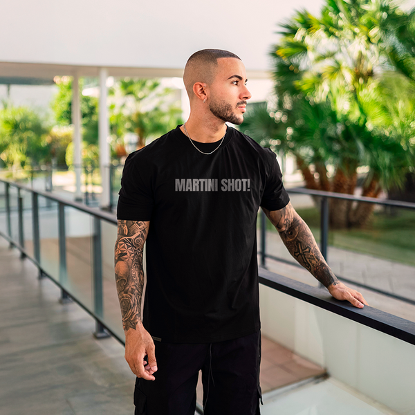Male model wearing a black 100% cotton t-shirt from Beard and Hat Actor with the phrase “MARTINI SHOT!” printed in light gray