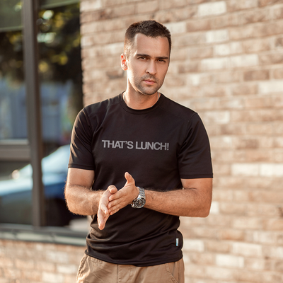 Male model wearing a black 100% cotton t-shirt from Beard and Hat Actor with the phrase “THAT’S LUNCH!” printed in light gray